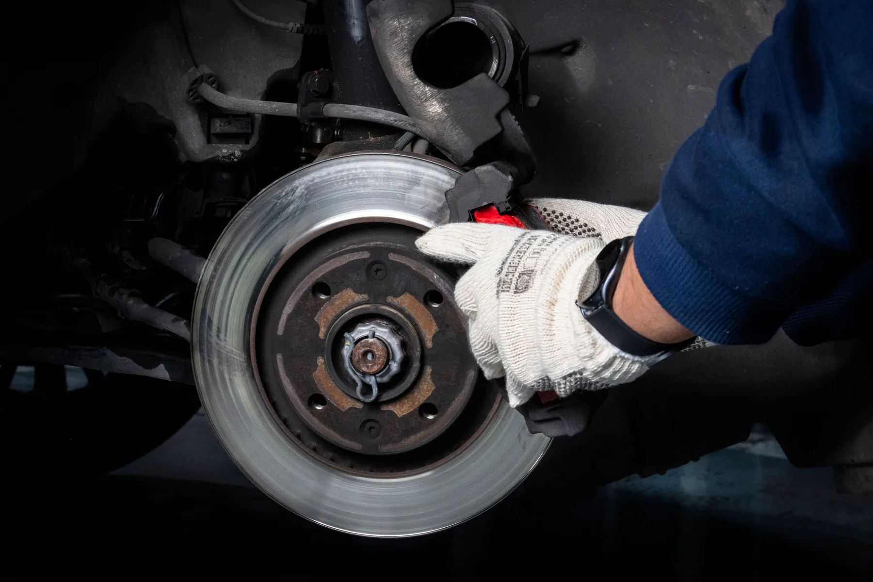 Hands performing brake service on a vehicle disc and caliper