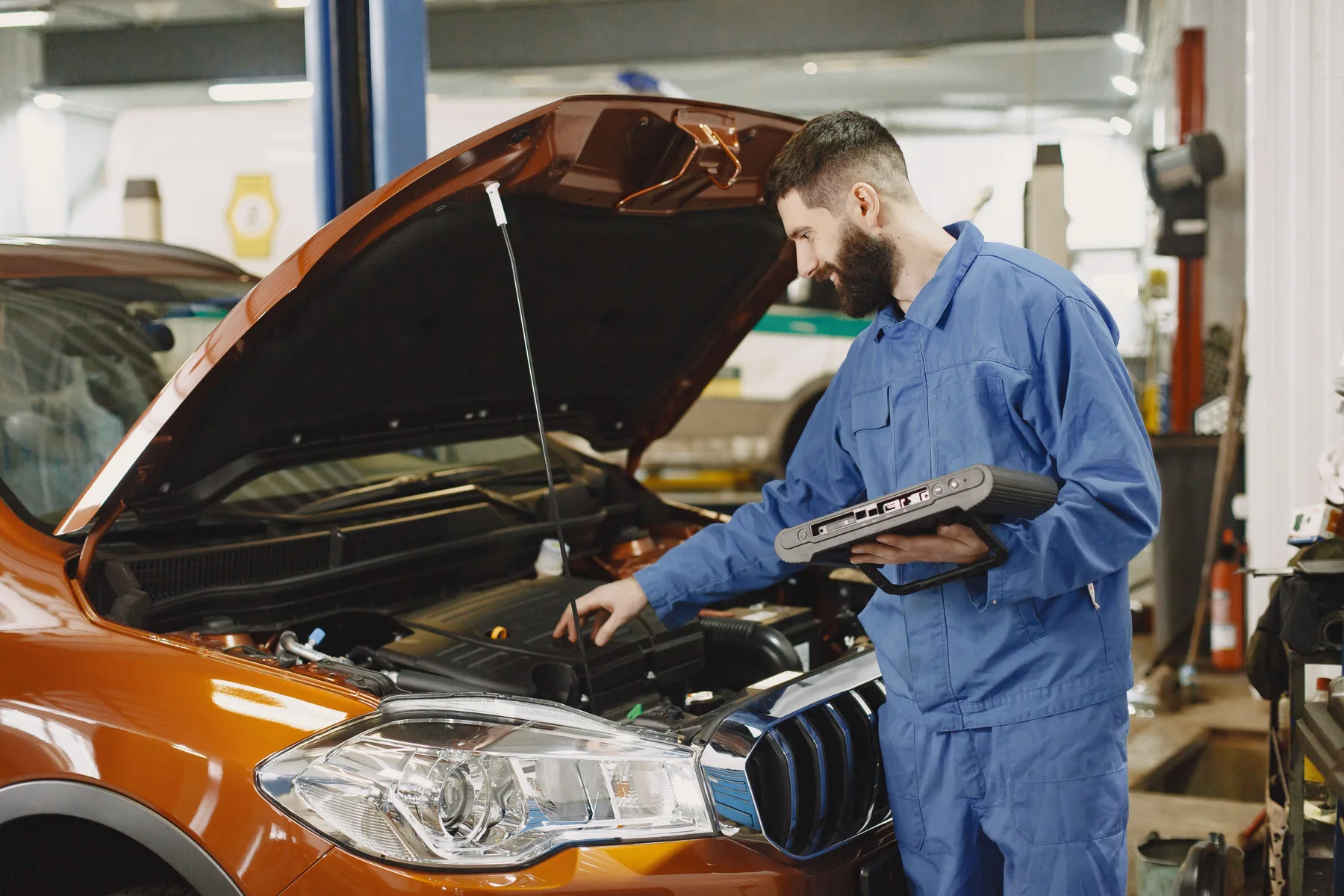 Mechanic performing automotive diagnostic testing under an open hood