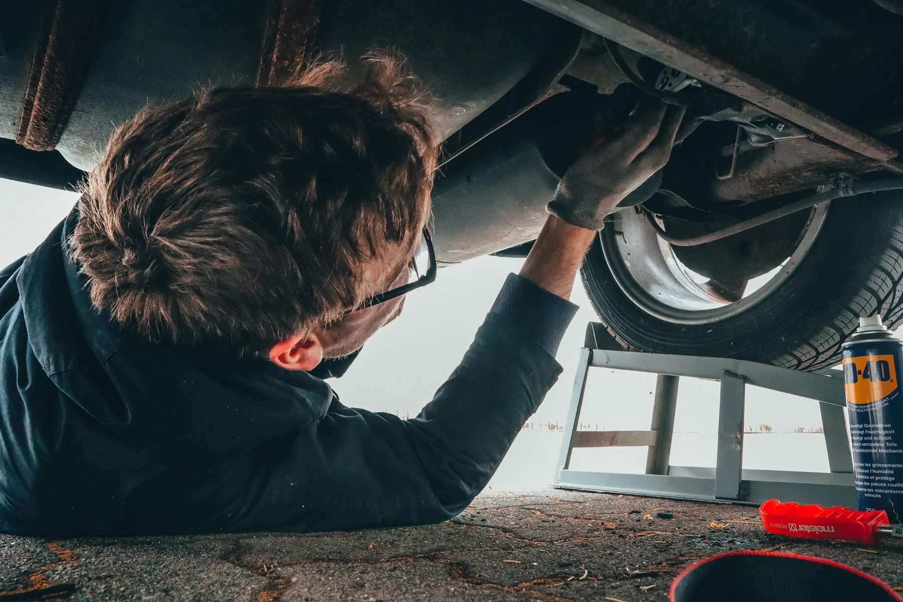 Mechanic repairing the underside of a vehicle outdoors