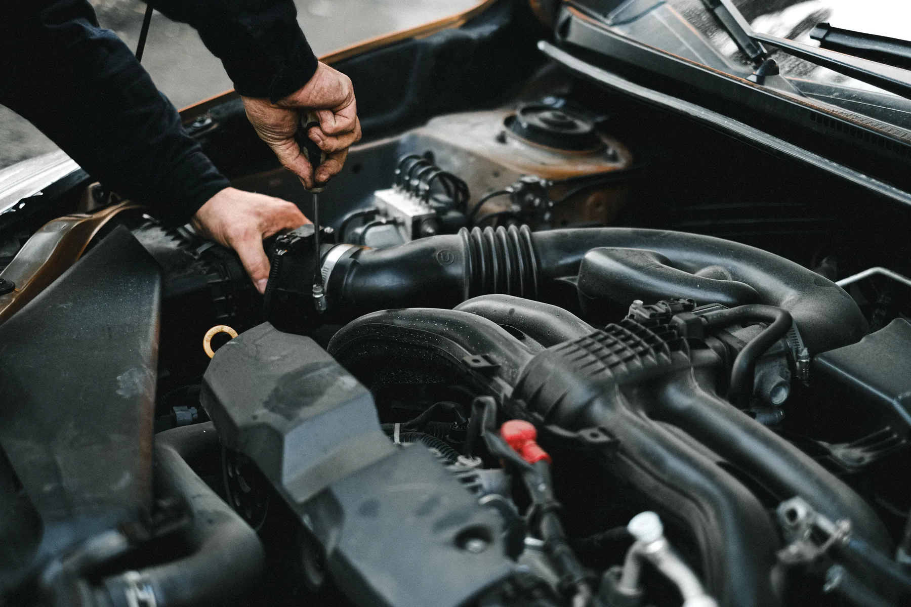 Hands working on an engine during automotive maintenance